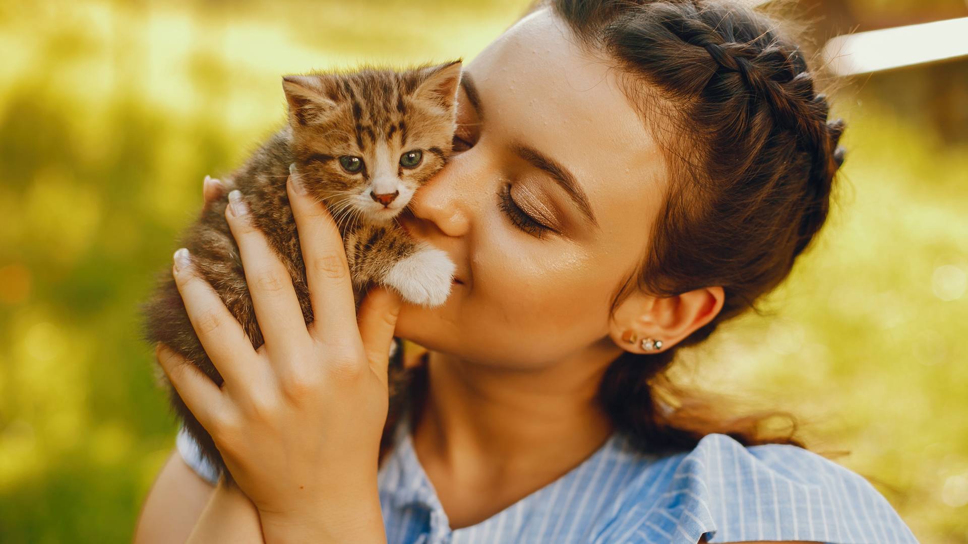woman affectionately holding kitten outdoors